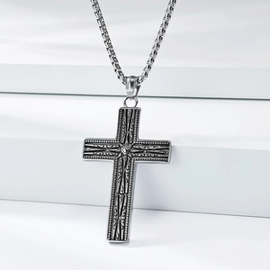 Détail du pendentif croix vintage avec motifs en relief et chaîne à mailles carrées