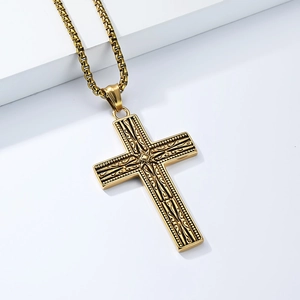 Gros plan détaillé d'un pendentif croix gothique dorée avec gravures vintage et chaîne boîte