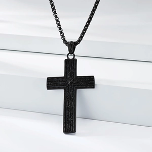Collier pendentif croix gothique noire avec motifs en relief sur support blanc minimaliste