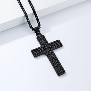 Détail d'un pendentif croix gothique noire avec gravures florales et chaîne perlée