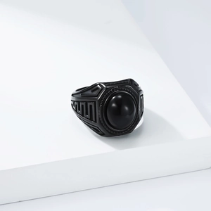 Macro detail of men's vintage black steel ring featuring round black stone and geometric patterns