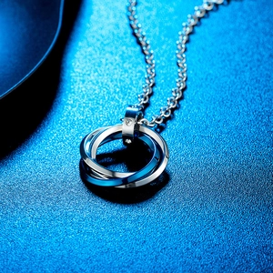 Macro shot of polished triple interlocked ring pendant with crystal connector on blue background