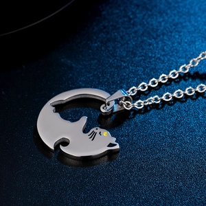 Macro shot of a silver cat-shaped pendant with yellow heart eyes and polished metal texture
