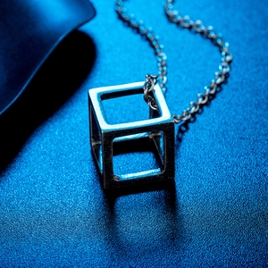 Macro detail of a silver stainless steel hollow cube pendant with sleek metal cross chain