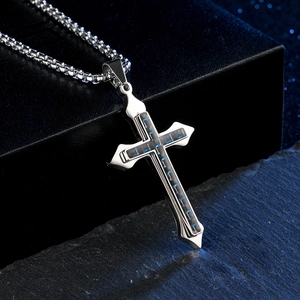 Détail d'un pendentif croix argenté avec insert en fibre de carbone bleue sur une chaîne box