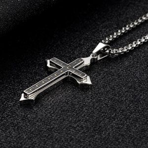 Vue macro du pendentif croix argentée avec texture en carbone sur chaîne à billes