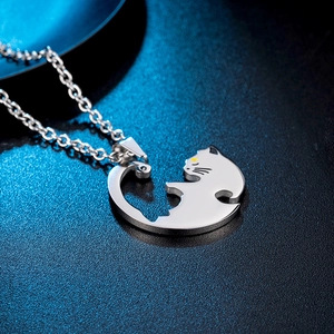 Macro view of silver titanium steel cat pendant with yellow eyes on black texture