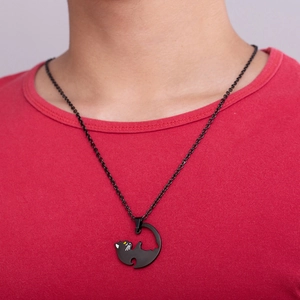Detail of a matte black moon-shaped cat pendant necklace worn on a red shirt
