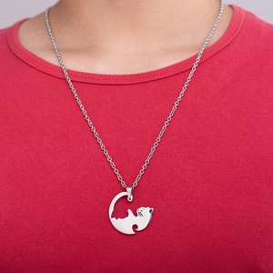Close-up of minimalist silver cat pendant necklace on model wearing red shirt