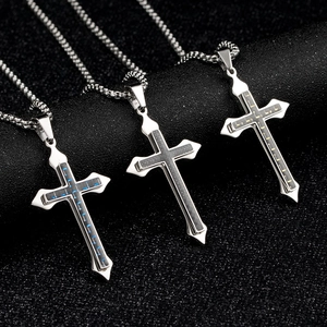 Trois colliers croix en fibre de carbone bleu, or et gris sur un support noir chic