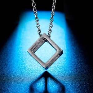 Minimalist geometric hollow cube pendant necklace in matte titanium steel on blue background