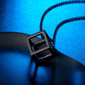 Minimalist black geometric cube pendant necklace in hollow stainless steel on blue glow