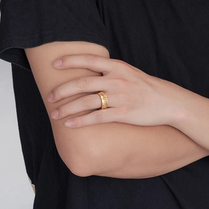 Detalle de un anillo giratorio vikingo dorado con textura de cadena en la mano de un hombre