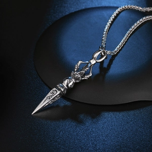 Macro view of vintage silver Vajra pestle pendant with Sanskrit carvings on black surface