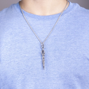 Detailed view of vintage Vajra pestle pendant on O-chain worn by male model