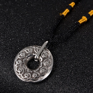 Vue détaillée d'un pendentif rond vintage avec gravures et cordon noir tressé