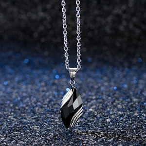 Macro view of faceted blue sand stone pendant with silver metal chain on bokeh background