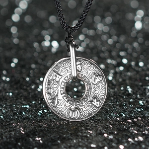 Vue détaillée du pendentif vintage en argent avec motifs de nuages et écritures