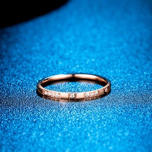 Gros plan d'une bague fine 2mm en or rose sertie de zircons sur fond bleu texturé
