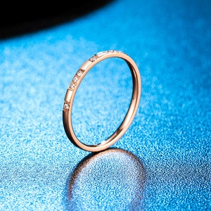 Vue macro d'une bague fine 2mm or rose avec cristaux sur fond bleu étincelant