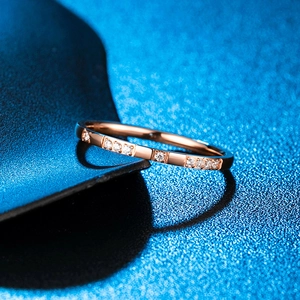 Vue macro d'une bague fine 2mm or rose avec zircons blancs sur un fond bleu texturé