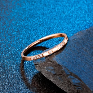 Vue macro d'une bague minimaliste 2mm en or rose sertie de zircons sur une pierre noire