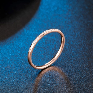 Bague minimaliste de 2 mm en or rose avec micro-zirconium sur fond texturé noir élégant