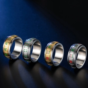 Close-up of four rotating stainless steel rings with traditional Mahjong motifs in gold and silver