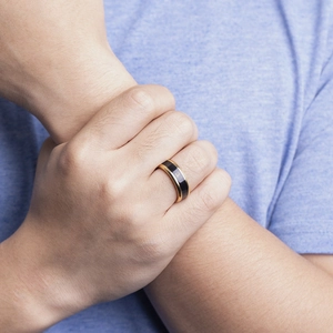 Detailansicht eines smarten Temperaturrings in Gold und Schwarz am Finger mit Logo