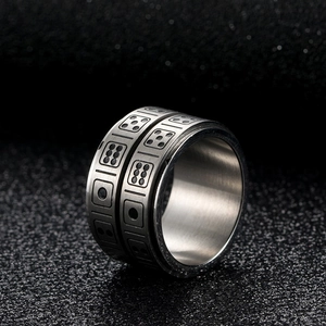 Macro view of rotating stainless steel dice ring with etched numbers on black texture