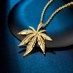Gros plan d'un pendentif feuille d'érable dorée avec des détails de texture précis