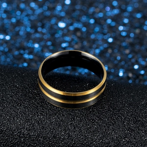 Dettaglio macro dell'anello da uomo in acciaio nero opaco e oro lucido su base nera