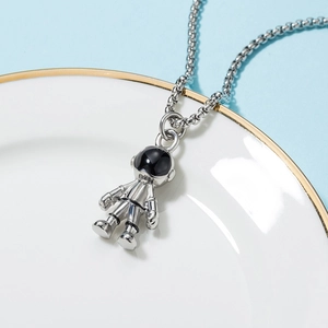 Macro shot of silver astronaut pendant with black enamel visor on a fine chain link