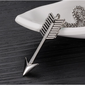 Vue macro d'un pendentif flèche vintage en acier titane avec empennage détaillé et fini poli