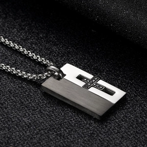 Macro detail of titanium cross pendant with black zircon inlays and brushed finish