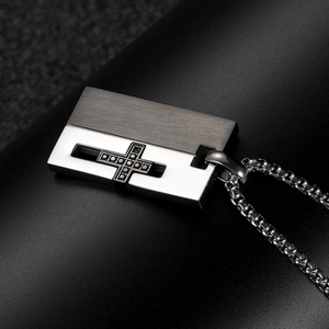 Macro detail of men's titanium cross pendant with brushed finish and black gemstone inlay