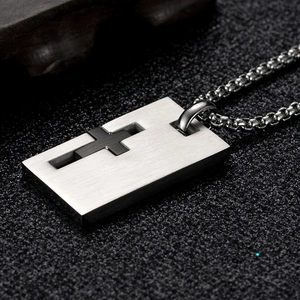 Macro detail of brushed titanium steel cross pendant with layered minimalist design