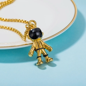 Golden astronaut pendant necklace on white ceramic tray with light blue background
