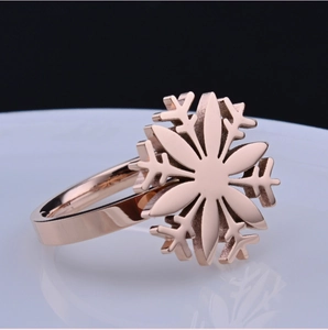 Elegant rose gold laser-cut snowflake ring displayed on a white plate with dark background