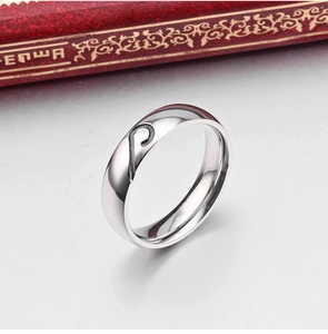 Detailed view of polished stainless steel couple ring with black half-heart pattern