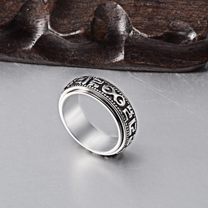 Detail of vintage spinning titanium steel ring with embossed ethnic mantras on wood