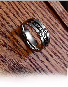 Macro shot of silver stainless steel ring featuring a black dragon pattern on dark wood