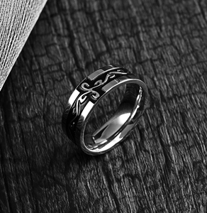 Macro shot of retro stainless steel ring with black cross and vine pattern on wood