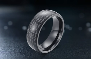 Macro shot of laser-engraved Buddhist scriptures on black stainless steel ring surface