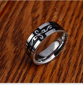 Polished silver stainless steel ring with black tribal cross pattern on wooden surface