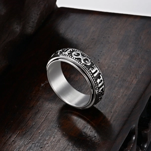 Vintage rotating stainless steel ring with embossed relief patterns on a wooden stand
