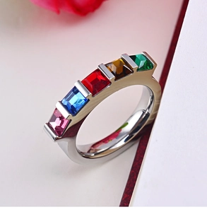 Bague en acier inoxydable avec cinq strass rectangulaires colorés sur fond blanc neutre