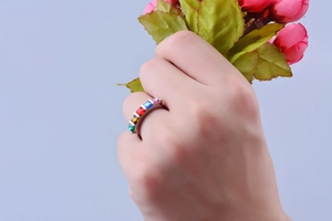 Détail d'une bague en acier avec cinq pierres rectangulaires colorées serties rail