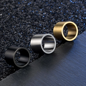 Macro shot of brushed titanium steel rings in black, silver, and gold on dark stone