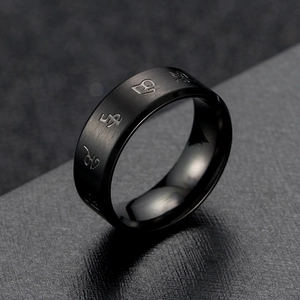 Macro shot of black stainless steel ring featuring brushed texture and engraved mantras